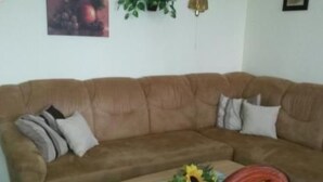 Ein braunes Sofa mit Kissen und ein kleiner Holztisch mit einer Sonnenblumenkomposition.