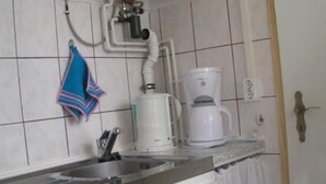 Eine Küche mit einer Kaffeemaschine, einem Durchlauferhitzer und einem Handtuch an der Wand.