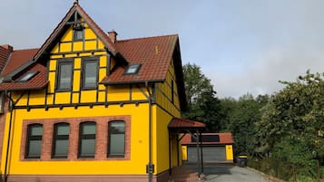 Ein gelbes Gebäude mit rotem Dach, einer Garage und einer Auffahrt.