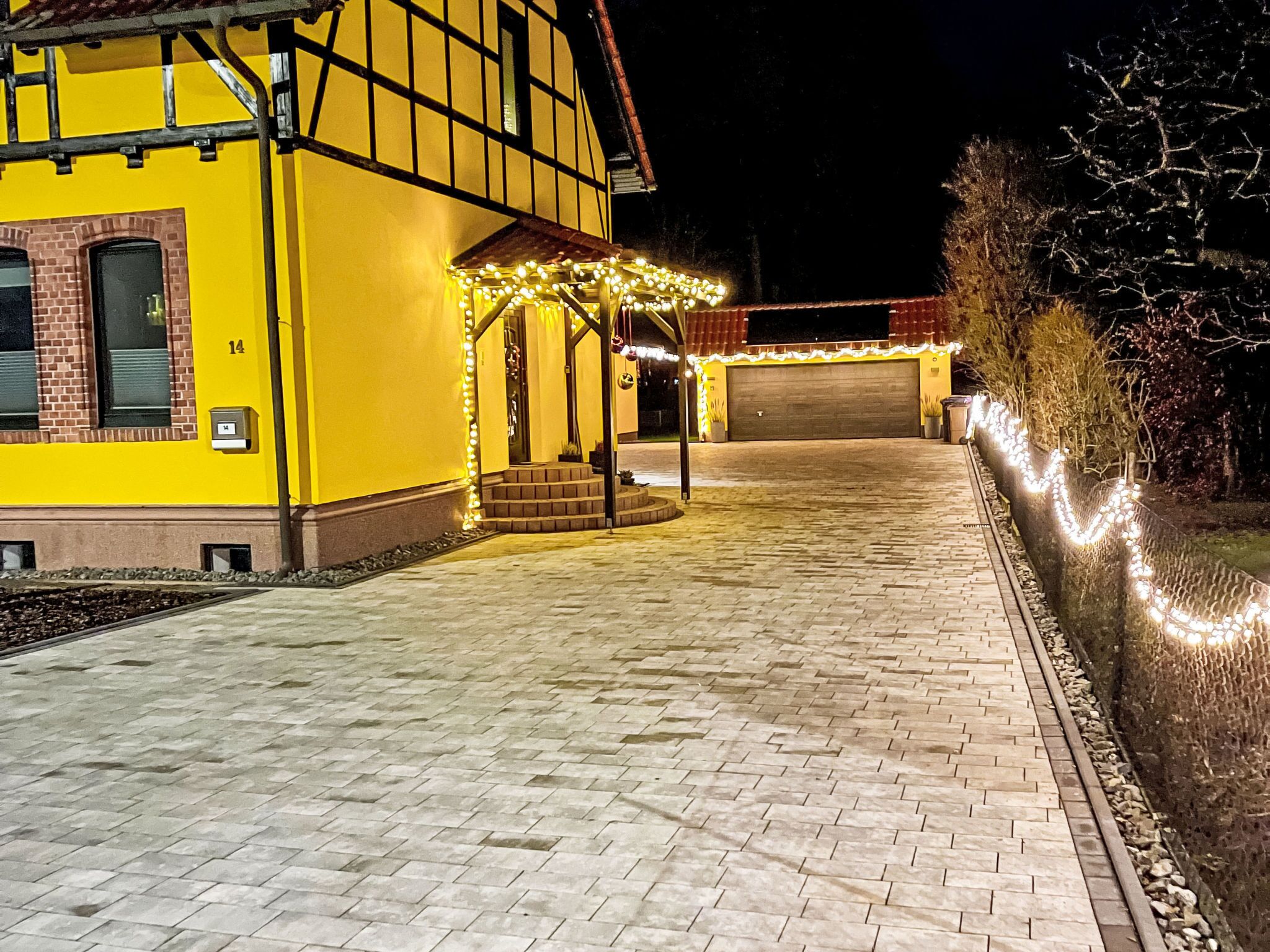 Un bâtiment jaune avec une entrée abritée et une allée pavée.