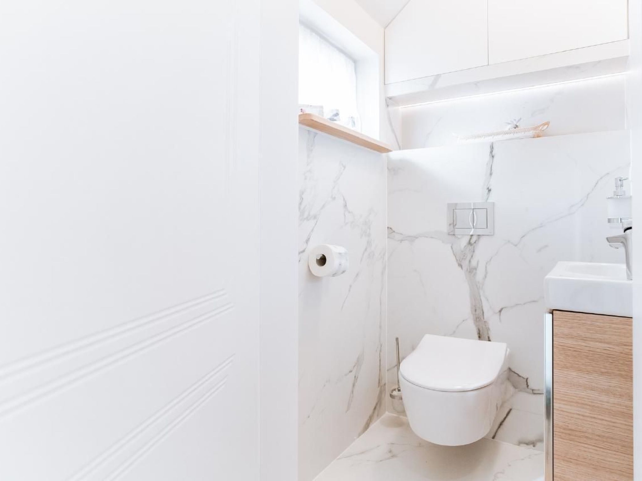 A modern bathroom with a toilet, sink, and marble walls.