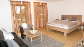 A modern bedroom with a bed, a sofa, a small table, and curtains. - Haus Annemarie by Interhome (Philippsreut)