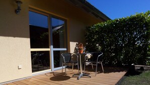 A wooden deck with a table and chairs, a glass door, and a large window. - mit Garten in ruhiger Lage by Interhome (Bansin)