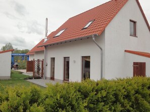 A two-story house with a red-tiled roof, white exterior walls, and a small front porch. - am Wasser mit Terrasse und Kaminofen by Interhome (Rechlin)