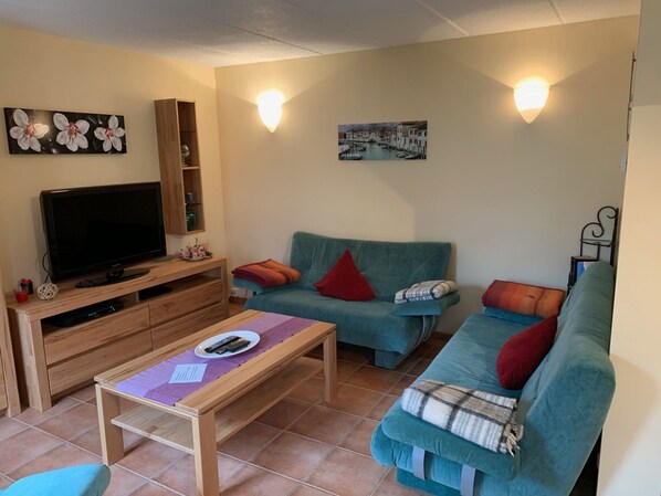 A living room with a TV, two sofas, a coffee table, and wall-mounted lights. - am Wasser mit Terrasse und Kaminofen by Interhome (Rechlin)