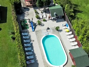 An aerial view of a swimming pool area with lounge chairs, a pool, and a small building. - Apartment am See by Interhome (Balatonmariafurdo)