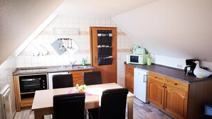 Cocina compacta con comedor, que incluye microondas, tostadora, pileta y muebles de madera.