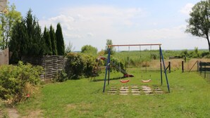 Un parque infantil con columpios y un tobogán, rodeado de césped y árboles.