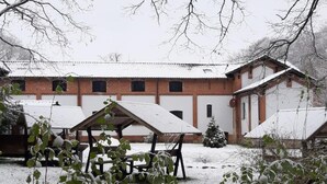 Ein verschneiter Innenhof mit einem Backsteinhaus, einer überdachten Sitzgelegenheit und einem Weihnachtsbaum.