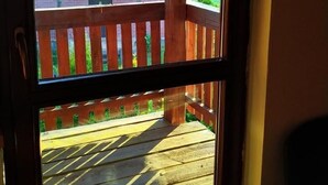 Una terraza de madera con vistas a una casa de ladrillo con balcón.