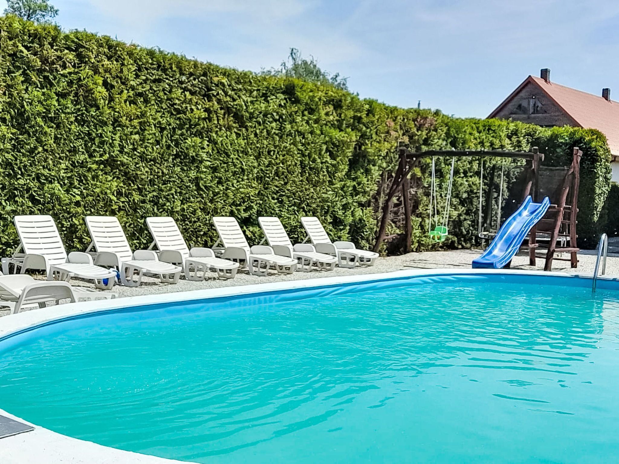 A swimming pool with lounge chairs and a slide.