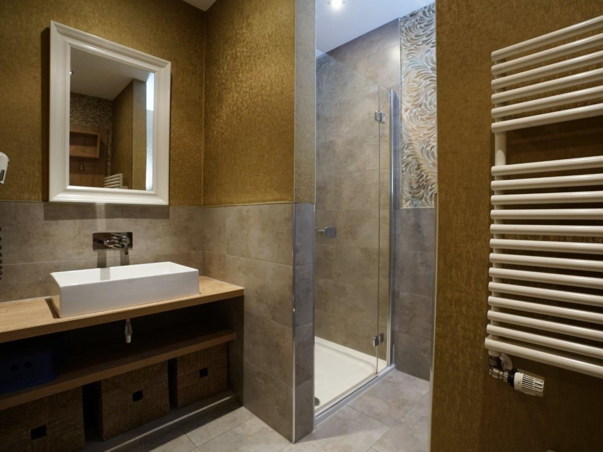 A modern bathroom with a large mirror, a sink, a shower enclosure, and a towel rack.