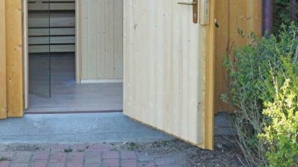 A wooden structure with a tiled roof and a circular door. - Maisonette  Seebrise mit Seeblick am Strand by Interhome (Flessenow)