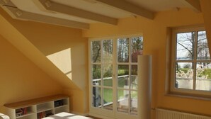 A spacious room with a large window, a white radiator, and a wooden table. - Maisonette  Seebrise mit Seeblick am Strand by Interhome (Flessenow)