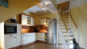 A kitchen with white cabinets, a stainless steel refrigerator, and a wooden staircase. - Maisonette  Seebrise mit Seeblick am Strand by Interhome (Flessenow)