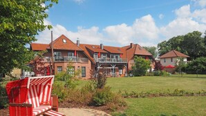 A large house with a spacious backyard, a covered seating area, and a well-maintained lawn. - Maisonette  Seebrise mit Seeblick am Strand by Interhome (Flessenow)