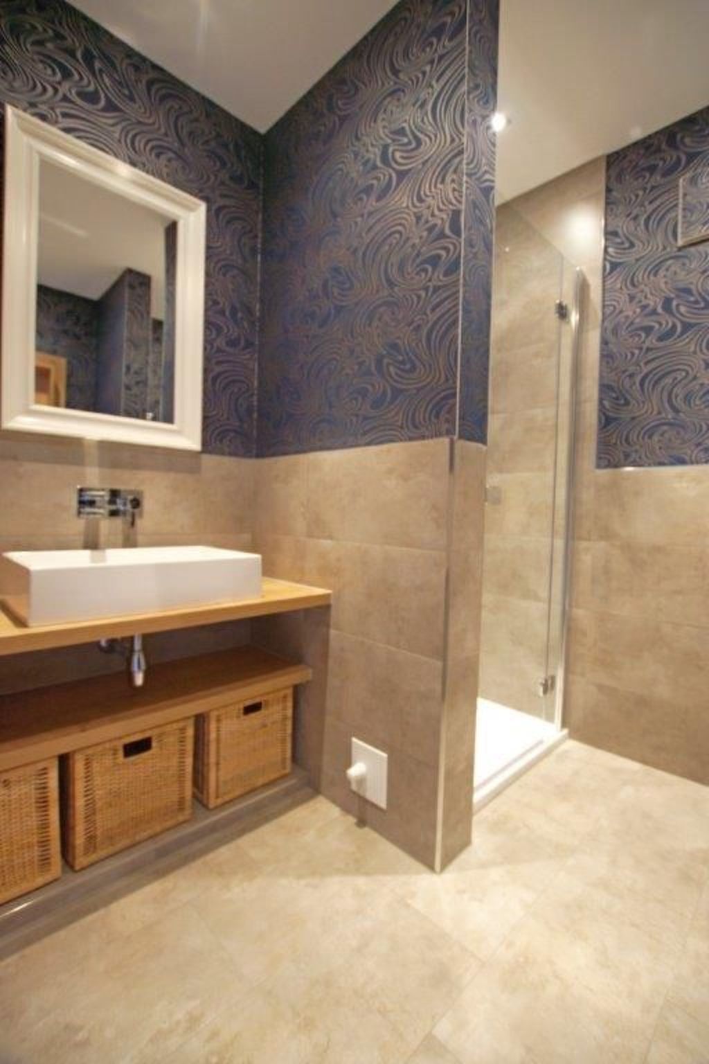 A bathroom with a white sink, a mirror, a shower, and patterned walls.