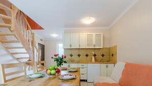 Una cocina moderna con armarios de madera, una mesa de comedor con sillas y una escalera.