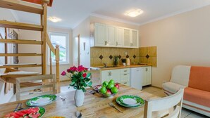 Comedor con mesa de madera dispuesta para una comida, un jarrón de flores y un frutero.