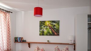 A bedroom with a bed, a red pendant light, a bookshelf, a wall-mounted picture, and a window with curtains. - Haus am Stein Haus 2 by Interhome (Königstein)