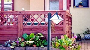 A wooden deck with a lattice railing, potted plants, and a door. - Haus am Stein Haus 2 by Interhome (Königstein)