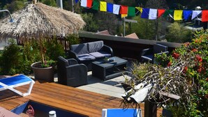 A rooftop terrace with outdoor furniture, a thatched umbrella, and colorful flags. - Haus am Stein Haus 2 by Interhome (Königstein)