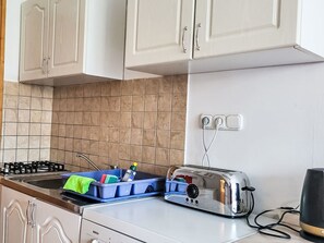 Eine Küche mit weißen Schränken, einem Bosch-Toaster und einem blauen Geschirrgestell.