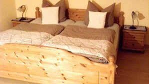 Un lit double avec une tête de lit en bois, deux tables de chevet avec des lampes et un tableau au mur.