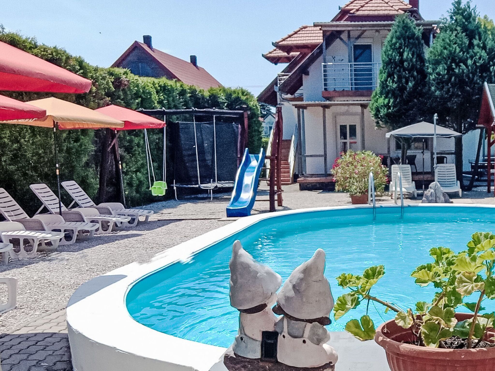 Une piscine avec des chaises longues, un toboggan et un bâtiment en arrière-plan.