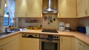 Une cuisine avec des meubles de couleur beige, une hotte de cuisinière en acier inoxydable, une machine à café et une bouilloire.