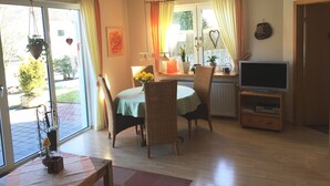 A dining area with wicker chairs, a table with a green tablecloth, and a television on a wooden stand. - Apartment Wiese by Interhome (Bruchhausen)