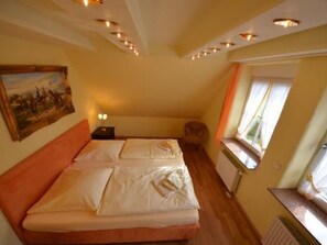 A bedroom with a double bed, a nightstand, a painting on the wall, and a window with curtains. - Sonnenkamp Maisonette by Interhome (Baabe)