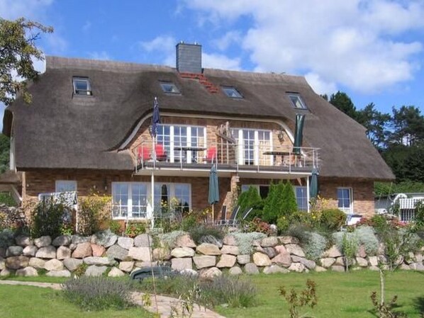 A two-story house with a stone facade, a thatched roof, and a balcony with railings. - Sonnenkamp Maisonette by Interhome (Baabe)