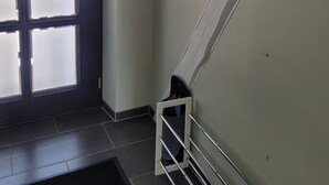 Ein Zimmer mit großem Fenster, weißer Wand und einem Metallregal.
