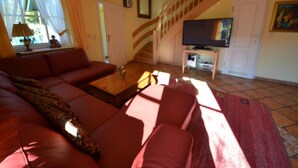 A living room with a sofa, TV, and a staircase. - Haus Strandhafer by Interhome (Baabe)