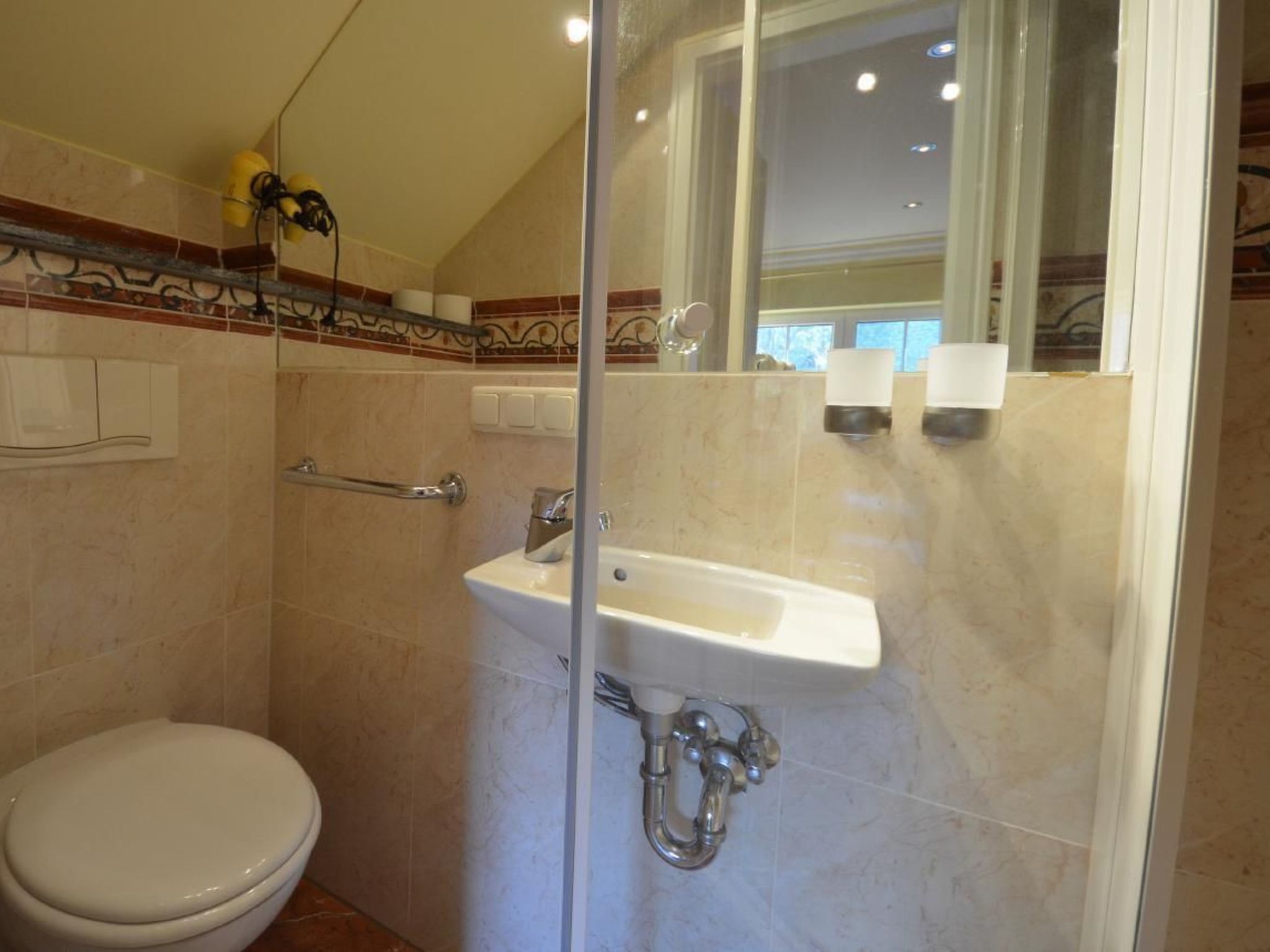 A bathroom with a glass shower enclosure, a white sink, and a toilet.