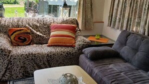 Een woonkamer met gestreepte banken, een bijzettafeltje met een decoratief object, en gordijnen.