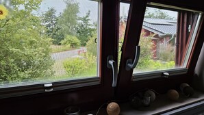 A train window with a view of greenery and a building. - Pinto Béla by Interhome (Twist)
