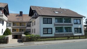 A multi-story residential building with a tiled roof, balconies, and a gated entrance.