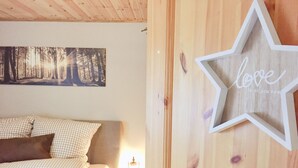 Ein Schlafzimmer mit einem Bett, einer sternförmigen Dekoration mit dem Wort 'love' an der Wand und einem Waldbild über dem Bett.