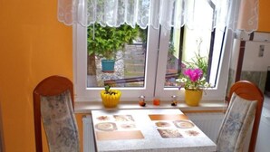 Un coin repas comprenant une table et deux chaises, une fenêtre agrémentée de plantes et une vue sur l’extérieur.