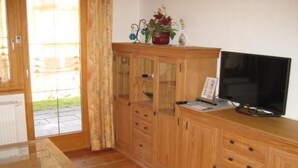 A wooden cabinet with glass doors, a television on top, and a small table with papers. - Chalet Sachrang by Interhome (Aschau im Chiemgau)