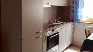 A kitchen with white cabinets, a countertop, a sink, and an oven. - Chalet Sachrang by Interhome (Aschau im Chiemgau)