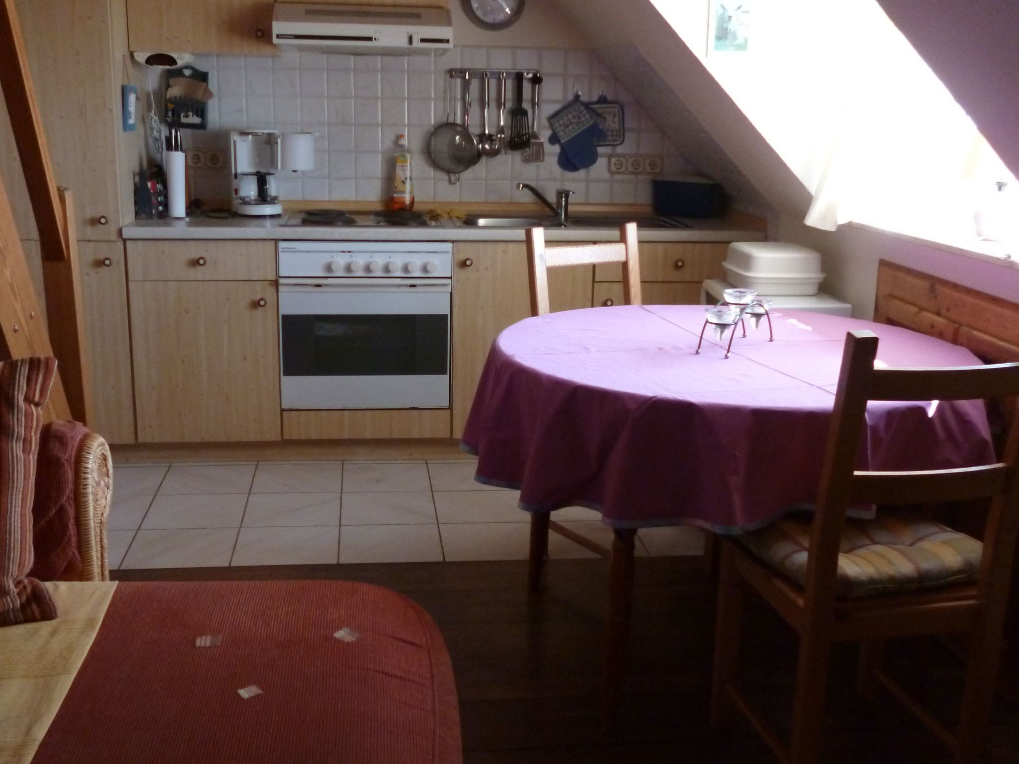 Een functionele keuken met een eethoek, met daarin een fornuis, oven en diverse keukengerei.