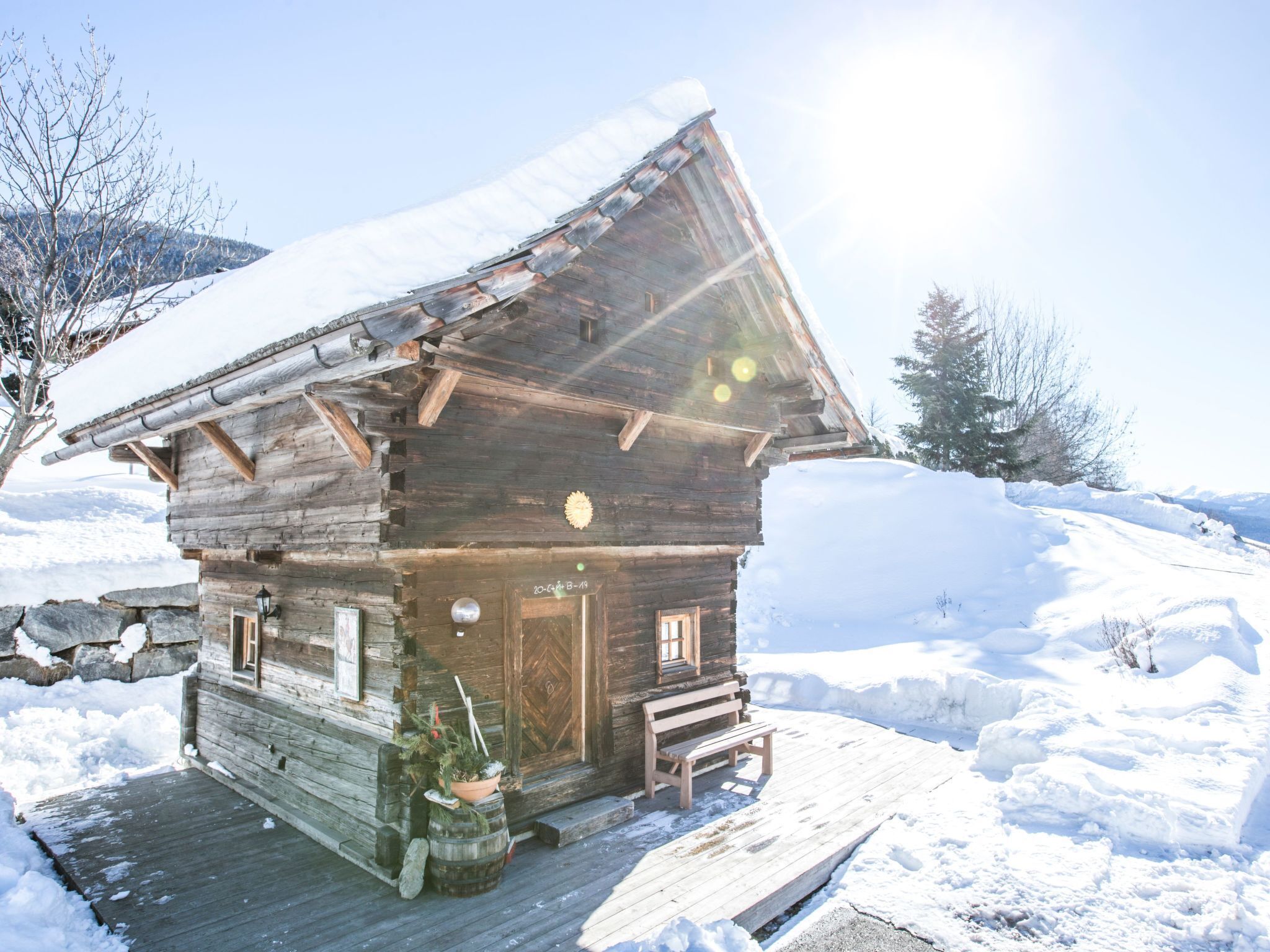 A rustic wooden cabin with a sloped roof, a wooden deck, and a bench outside.