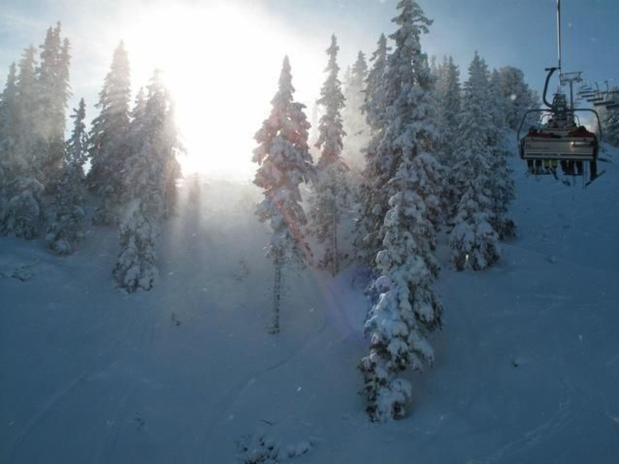 A snowy landscape with a ski lift and snow-covered trees.