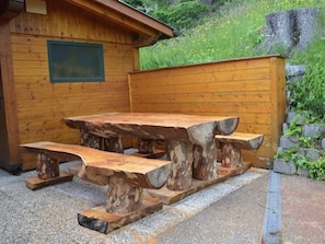 A wooden picnic table with benches, set against a wooden cabin backdrop. - Almhaus am Hohenwart by Interhome (Klippitztörl)