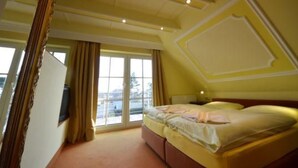 Ein Schlafzimmer mit einem großen Bett, einem Fenster mit Vorhängen und einer Decke mit Einbaustrahlern.