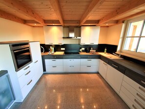 Een koelkast, een oven, een vaatwasser, kookgerei, borden en bestek