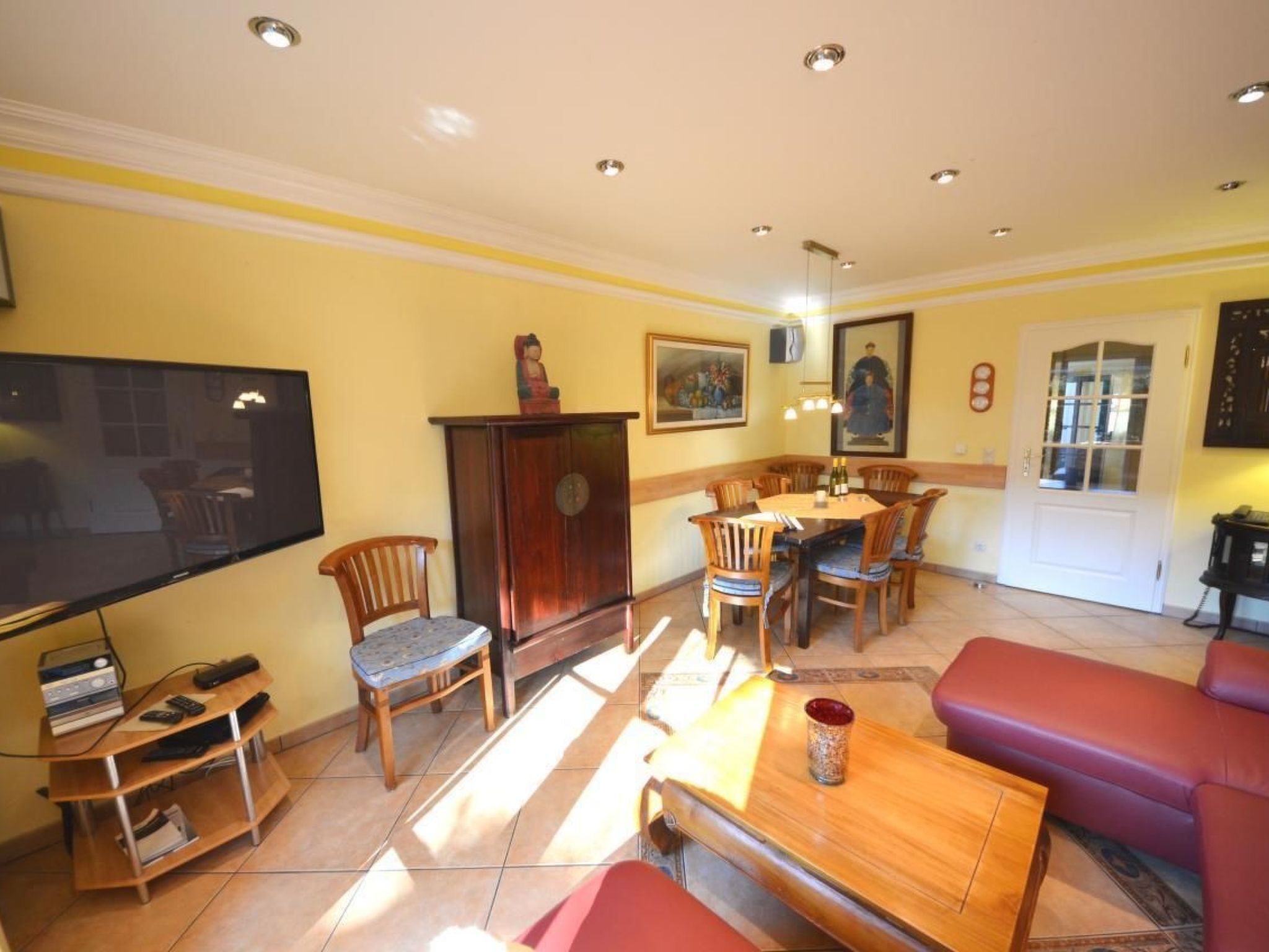 A living room with a TV, wooden furniture, a dining table, and a sofa.